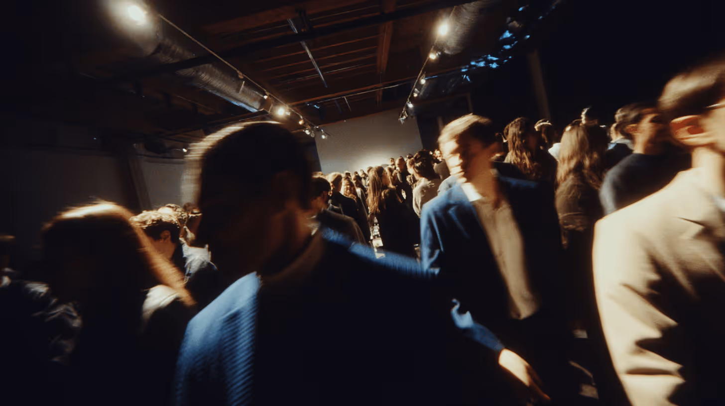 Personnes en mouvement dans une pièce sombre avec éclairage de plafond, créant un effet flou artistique.